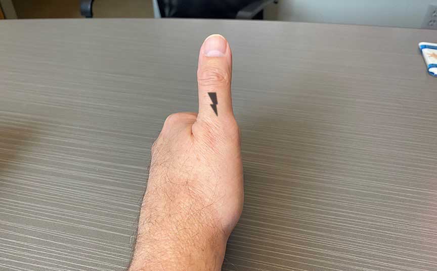 A man giving a thumbs up with a lightning bolt drawn on his left thumb